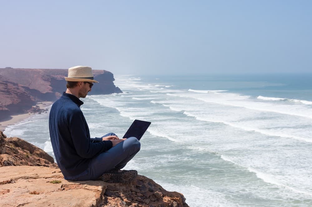 Voyageur au bord de la plage, sur son ordinateur