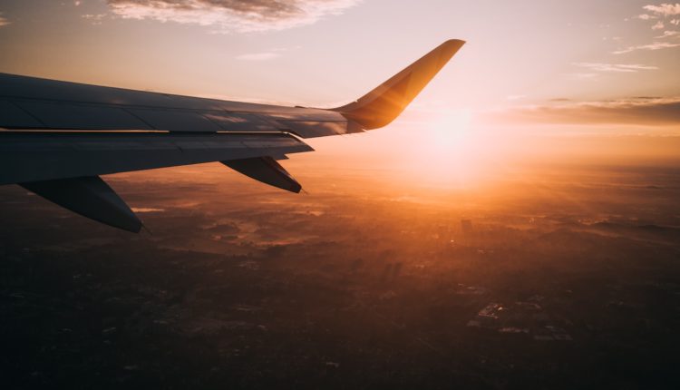 Une aile d'avion avec un coucher de soleil.