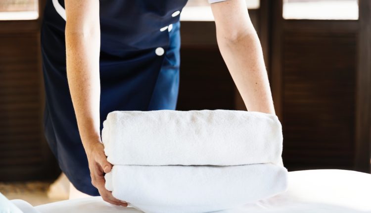 Femme de chambre en train de déposer des serviettes de toilette.