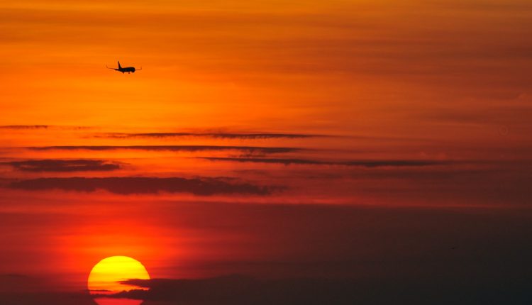 Avion devant un soleil couchant.
