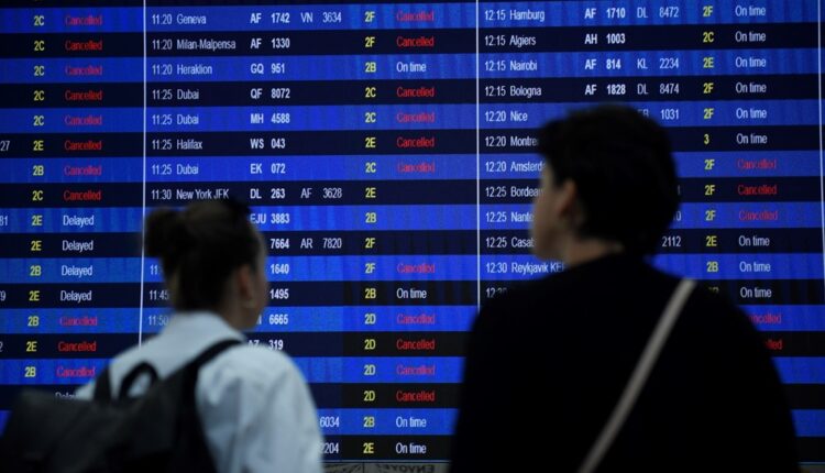 Des passants regardant le panneau d'information des départs du terminal 2 de l'aéroport Roissy-Charles de Gaulle, annonçant plusieurs annulations de vols suite à une grève des contrôleurs aériens. © Julien de Rosa / AFP